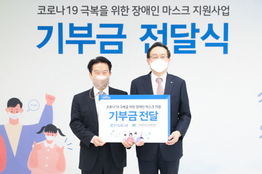 우리금융그룹은 4일 서울시 중구 소재 우리은행 본점에서 '코로나19 극복을 위한 장애인 마스크 지원사업' 기부금 전달식을 열었다. 손태승(오른쪽) 우리금융그룹 회장과 최공열(왼쪽) 한국장애인단체총연맹 상임대표가 기념촬영을 하고 있다. <우리금융그룹>